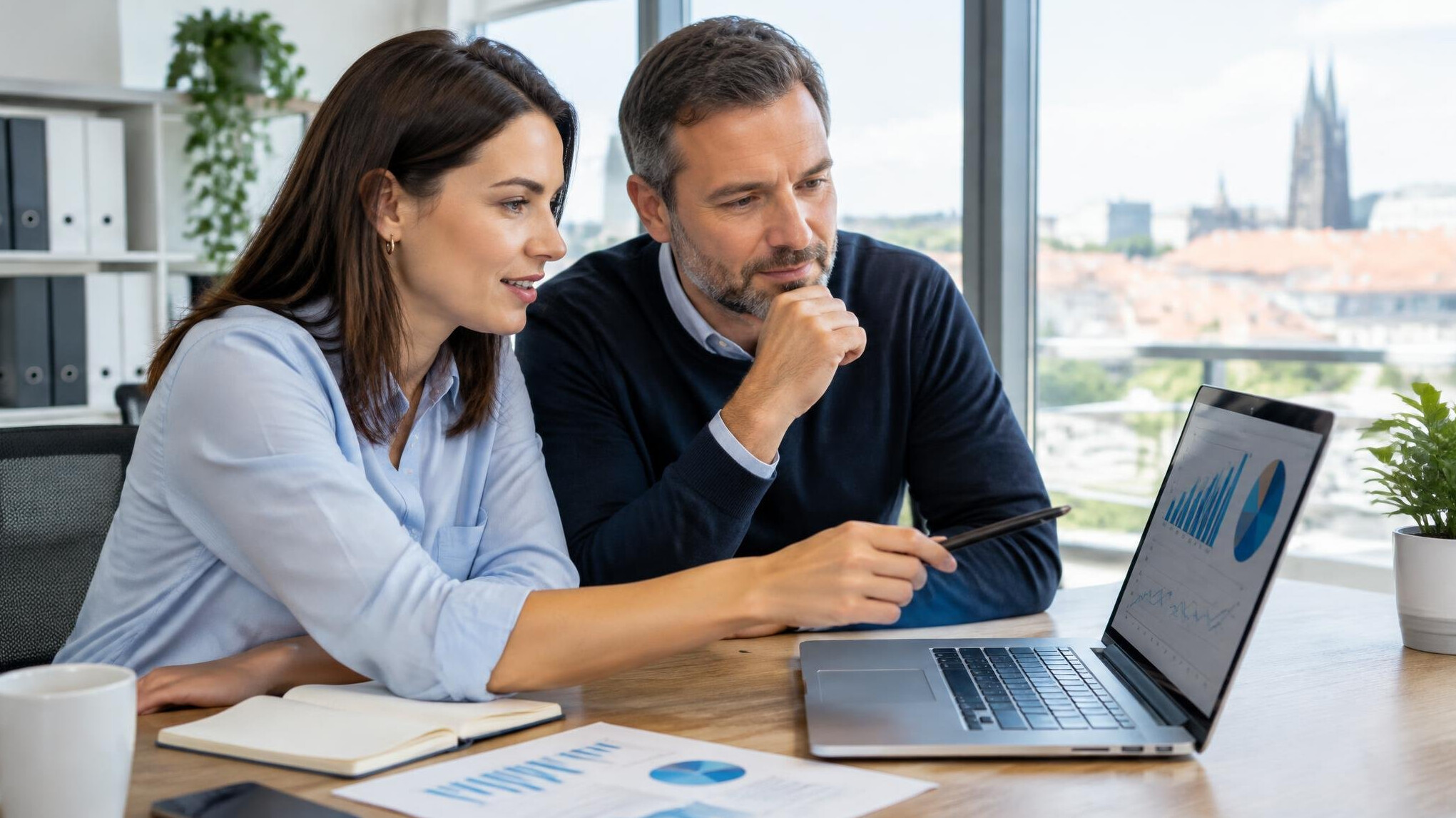 Two colleagues reviewing data on a laptop in a bright modern office